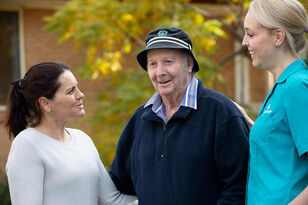 elderly resident smiling outside the nursing home with two aged care home employees